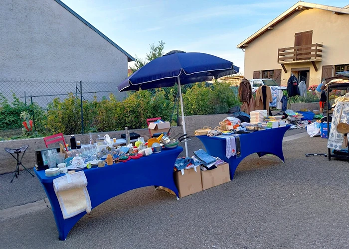 Stand particulier avec parasol, tables et housses lors d'un vide-greniers 